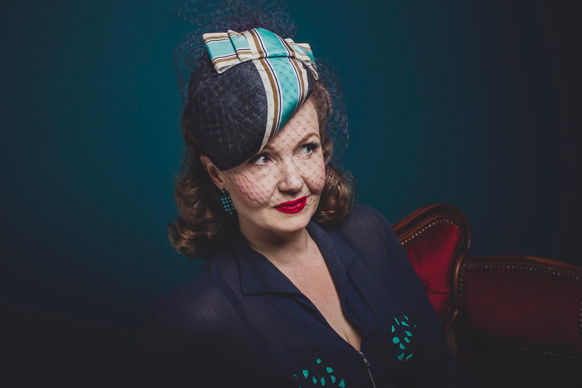 Lady wearing a navy hat decorated with a white and turquoise ribbon and a blue dress