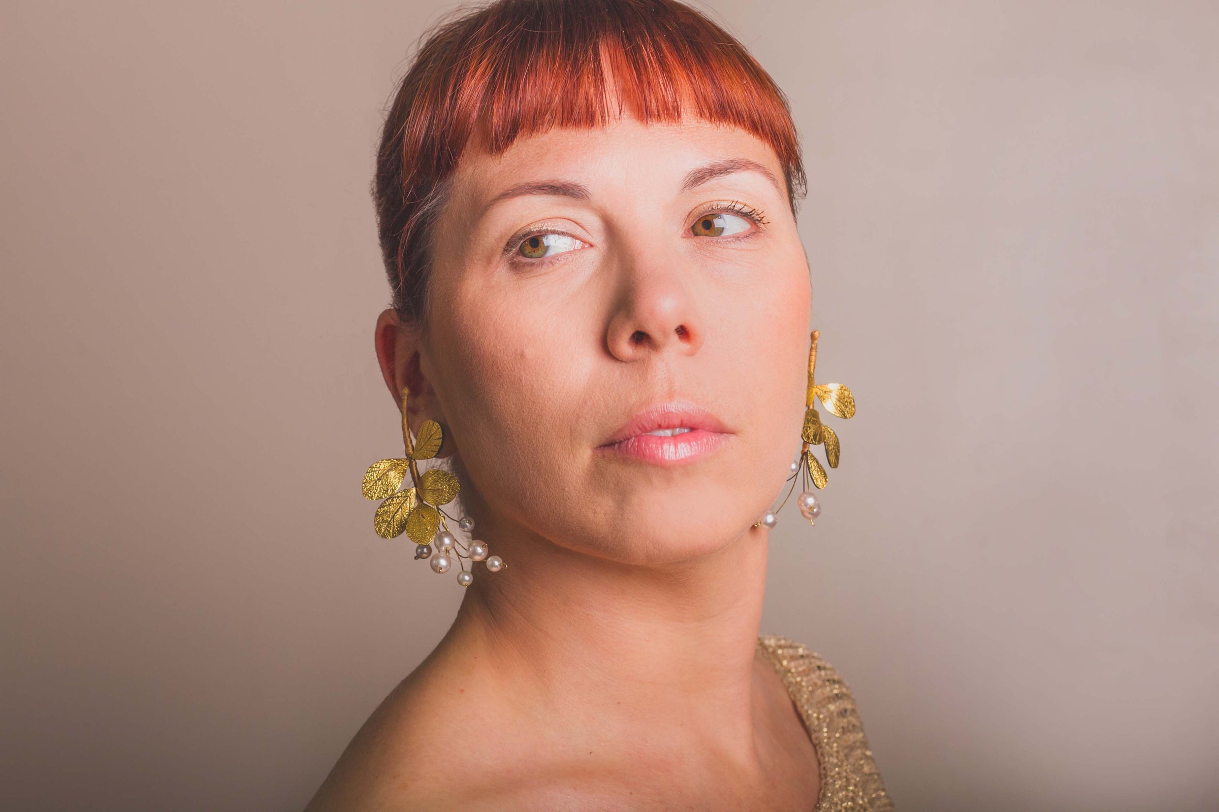 Women with red hair wearing large floral gold earrings