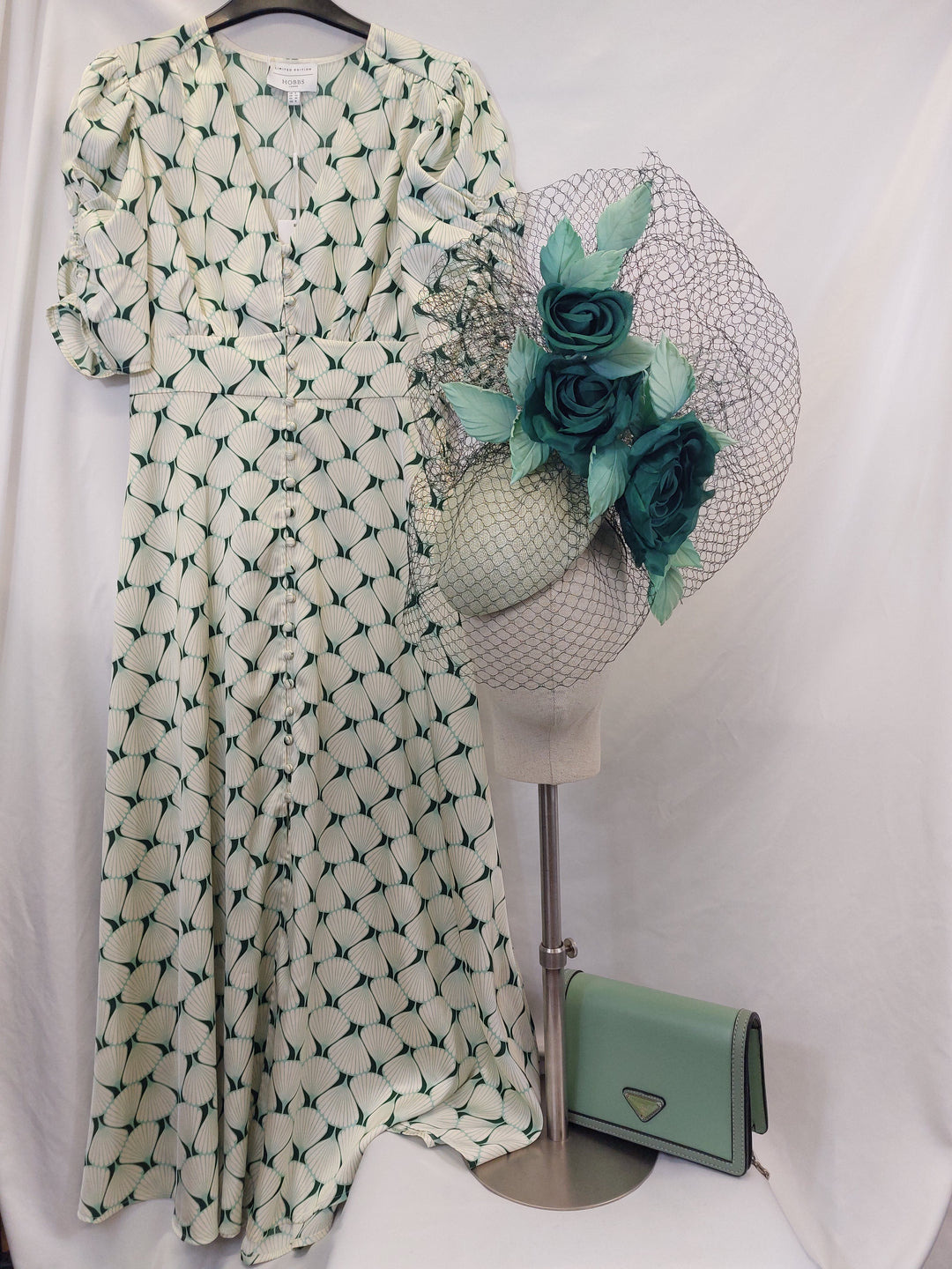 Green and white patterned dress with a decorative matching hat and purse on a white background
