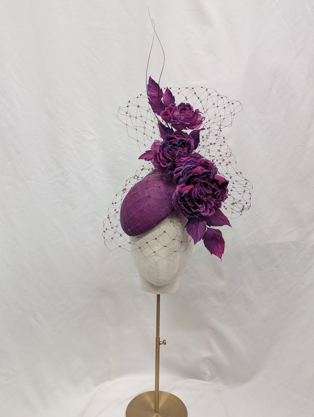 Purple floral headpiece on a mannequin against a white background
