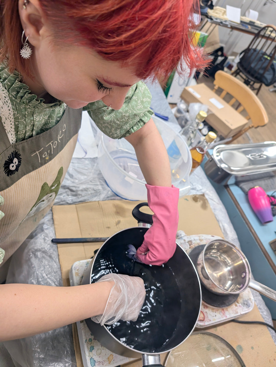 Person with red hair and dying fabric a pot 