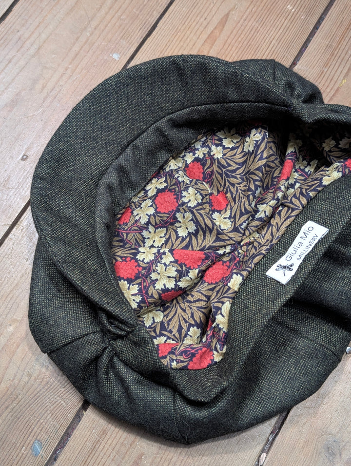 Dark gray flat cap with floral lining on a wooden surface