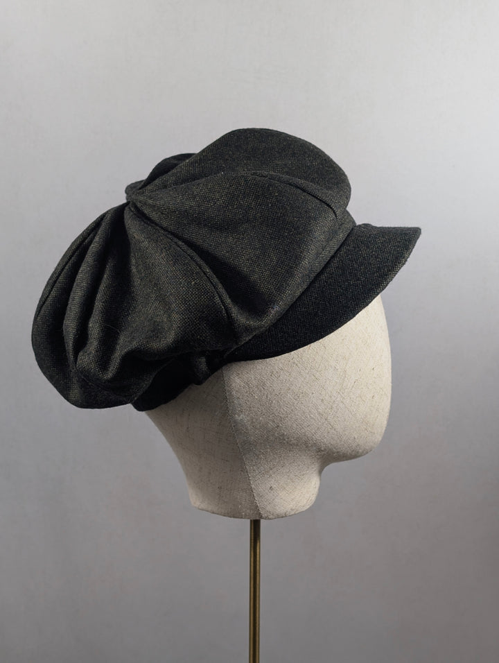 Dark gray hat on a mannequin head against a plain background