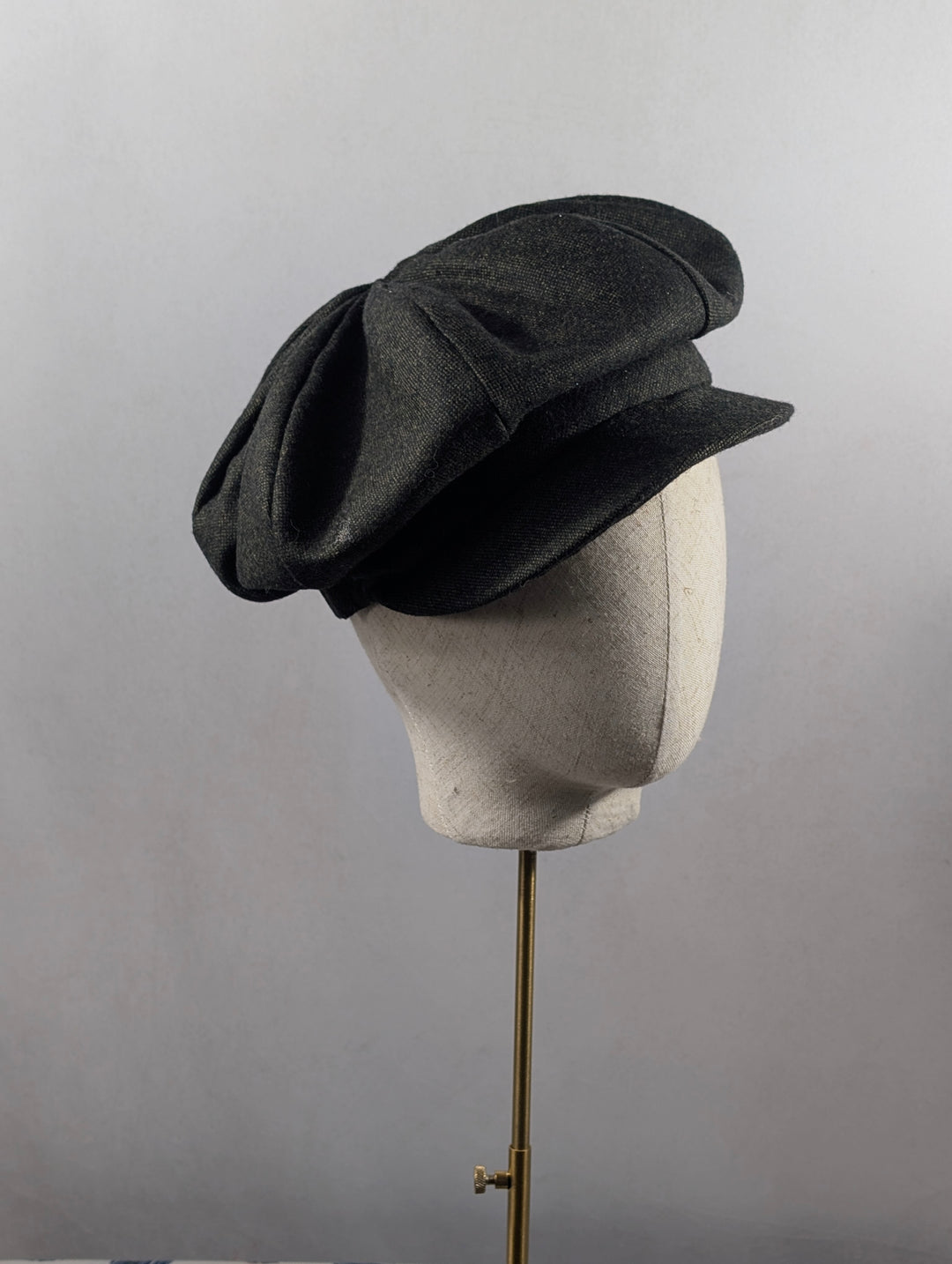 Dark gray hat on a mannequin head against a plain background