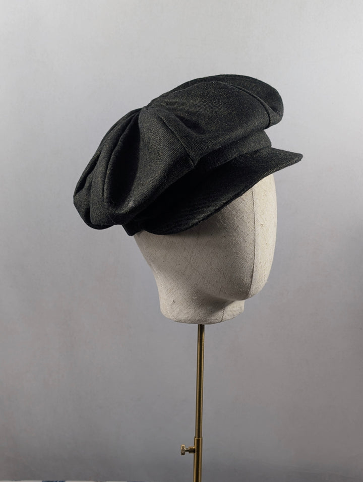Dark gray hat on a mannequin head against a plain background