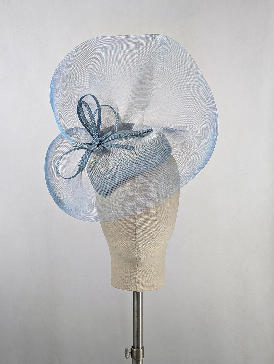 Light blue fascinator on a mannequin head against a plain background