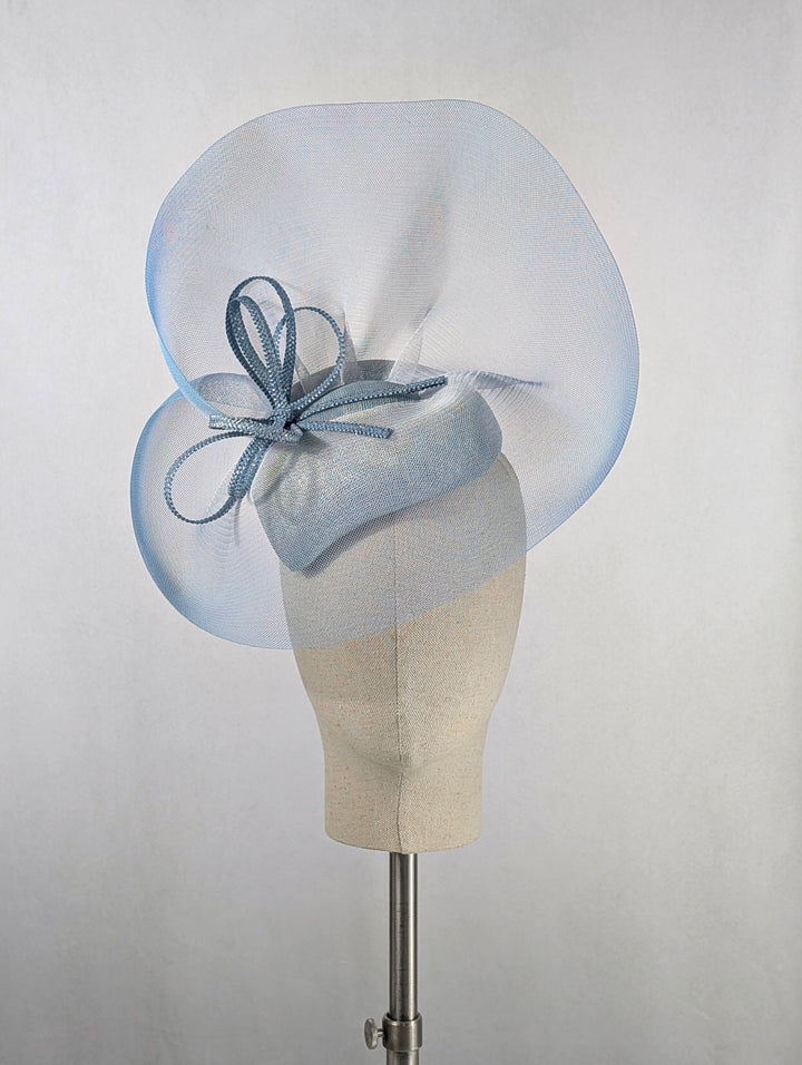 Light blue fascinator on a mannequin head against a plain background