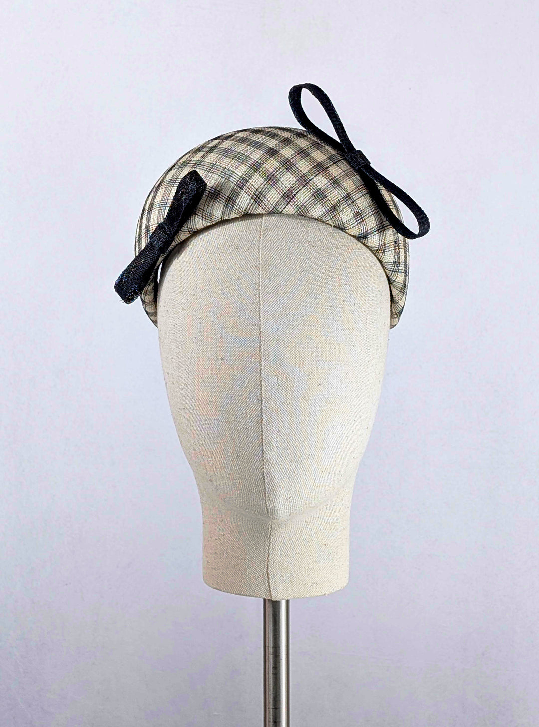 Plaid headband with bows on a mannequin head against a gray background
