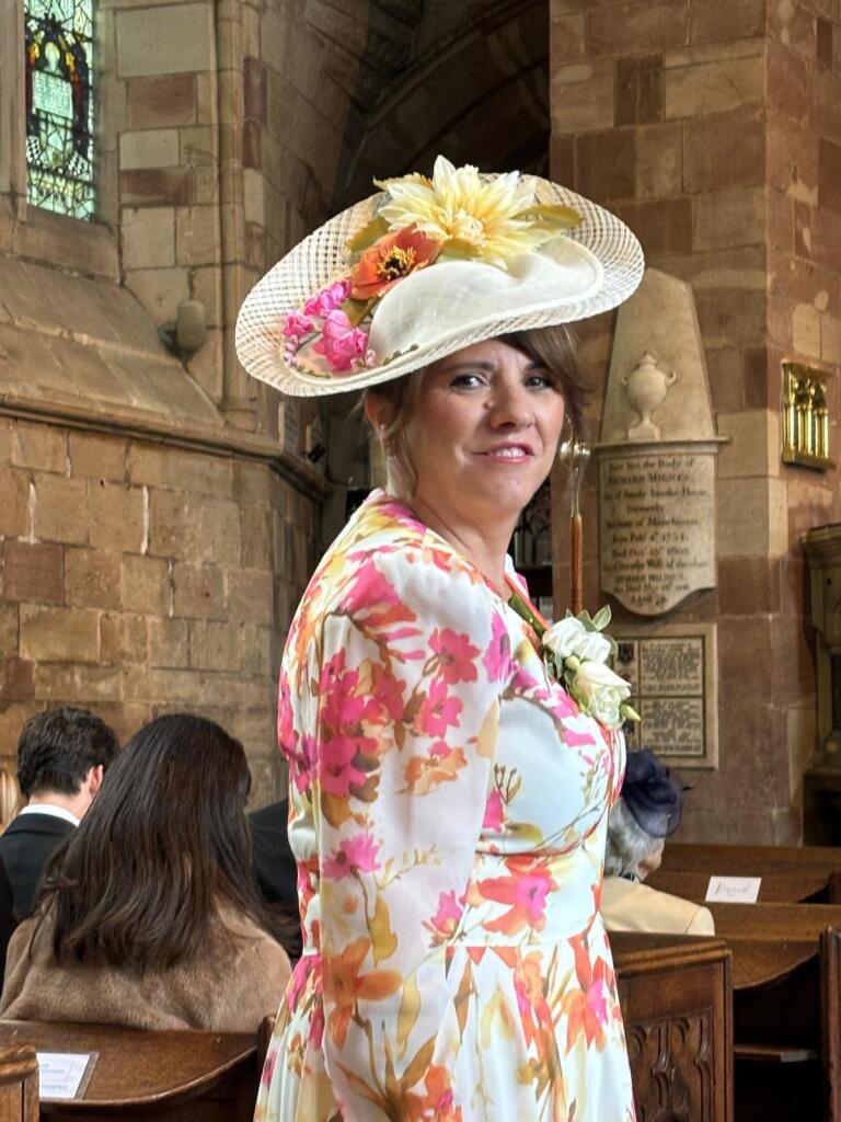 Woman wearing a floral dress and large hat in a church setting