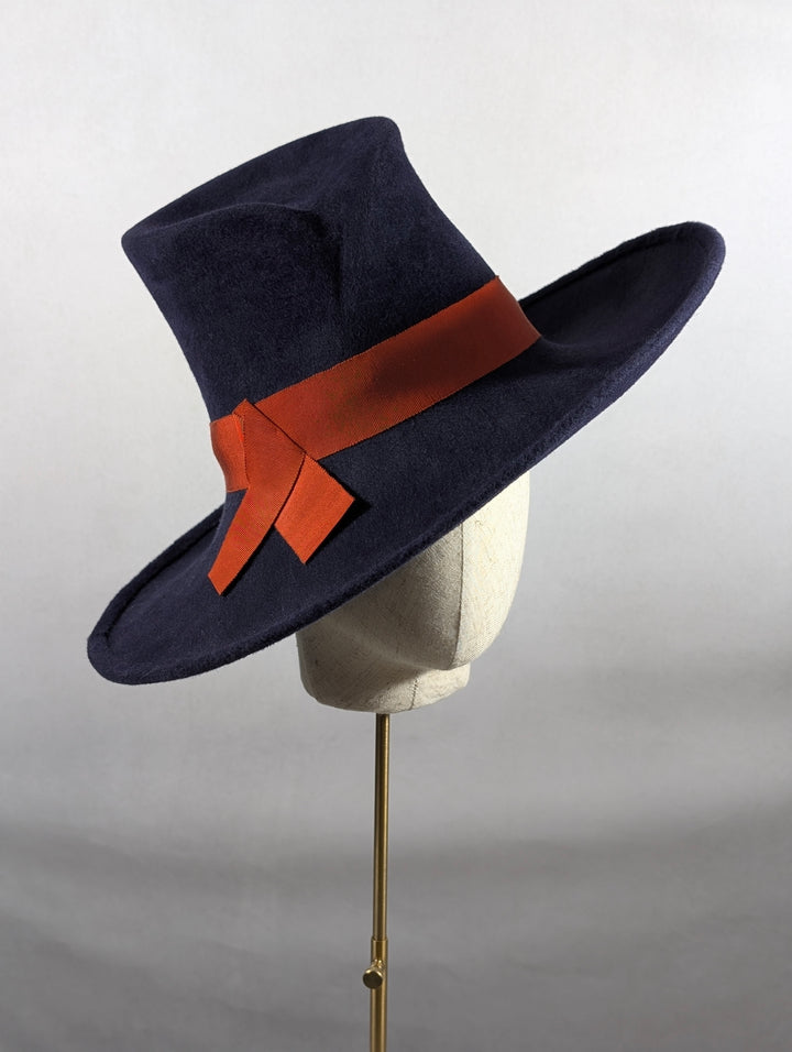 Navy blue hat with a red ribbon on a mannequin head against a white background