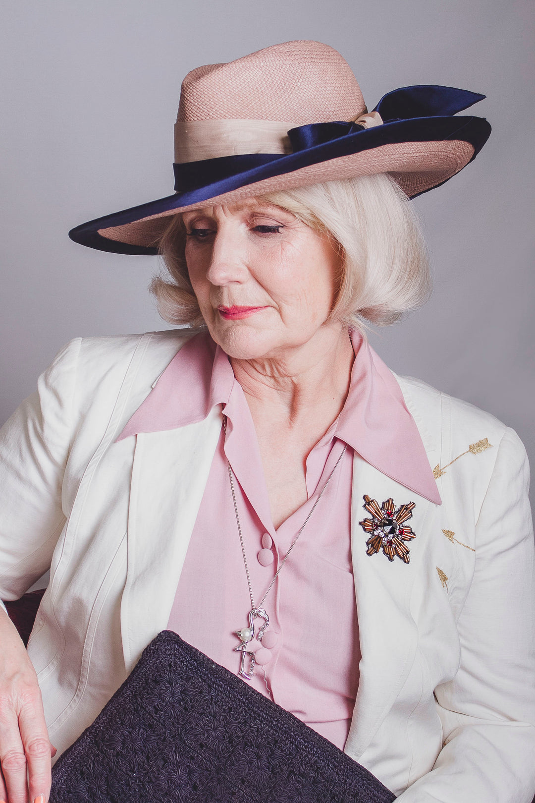 A woman wearing a dove grey Panama hat with navy blue silk trimming and a bow.